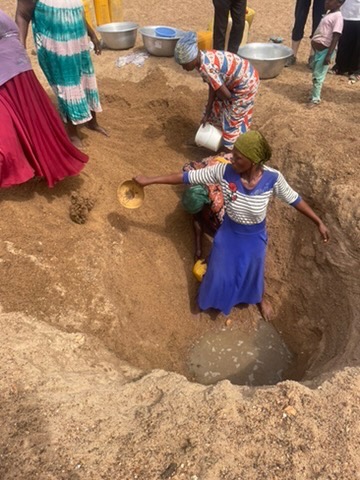 Women and children digging into the river bed for water